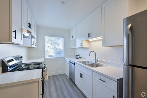 an empty kitchen with white cabinets and stainless steel appliances